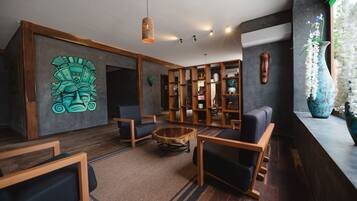 Een moderne lounge met houten meubels, een centrale salontafel en een decoratieve wand met een muurschildering.
