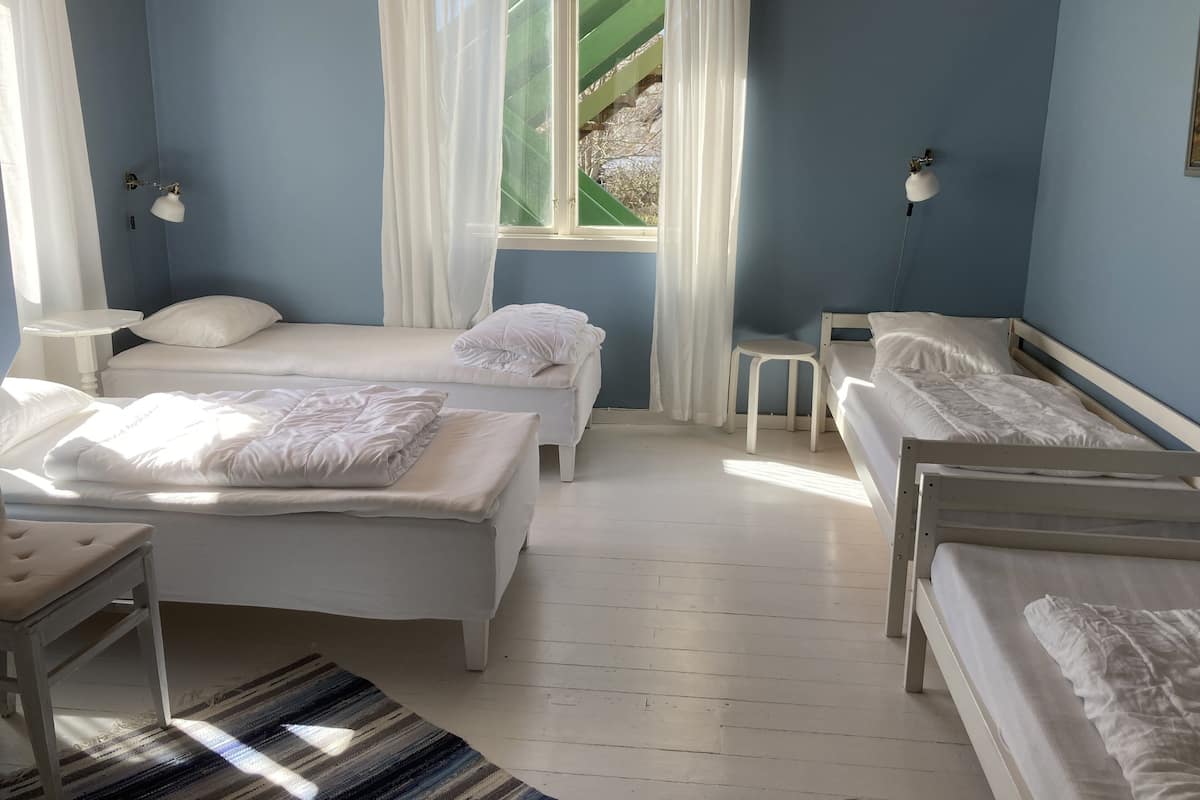 Una habitación con dos camas, una mesita, una lámpara y una ventana con cortinas.