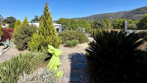 A garden with a variety of plants, a white gazebo, and a statue of a rabbit. - Casa Carvalhal - Adults Only (Góis)