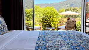 A bedroom with a large bed, a view of a garden, and a table with chairs outside. - Casa Carvalhal - Adults Only (Góis)