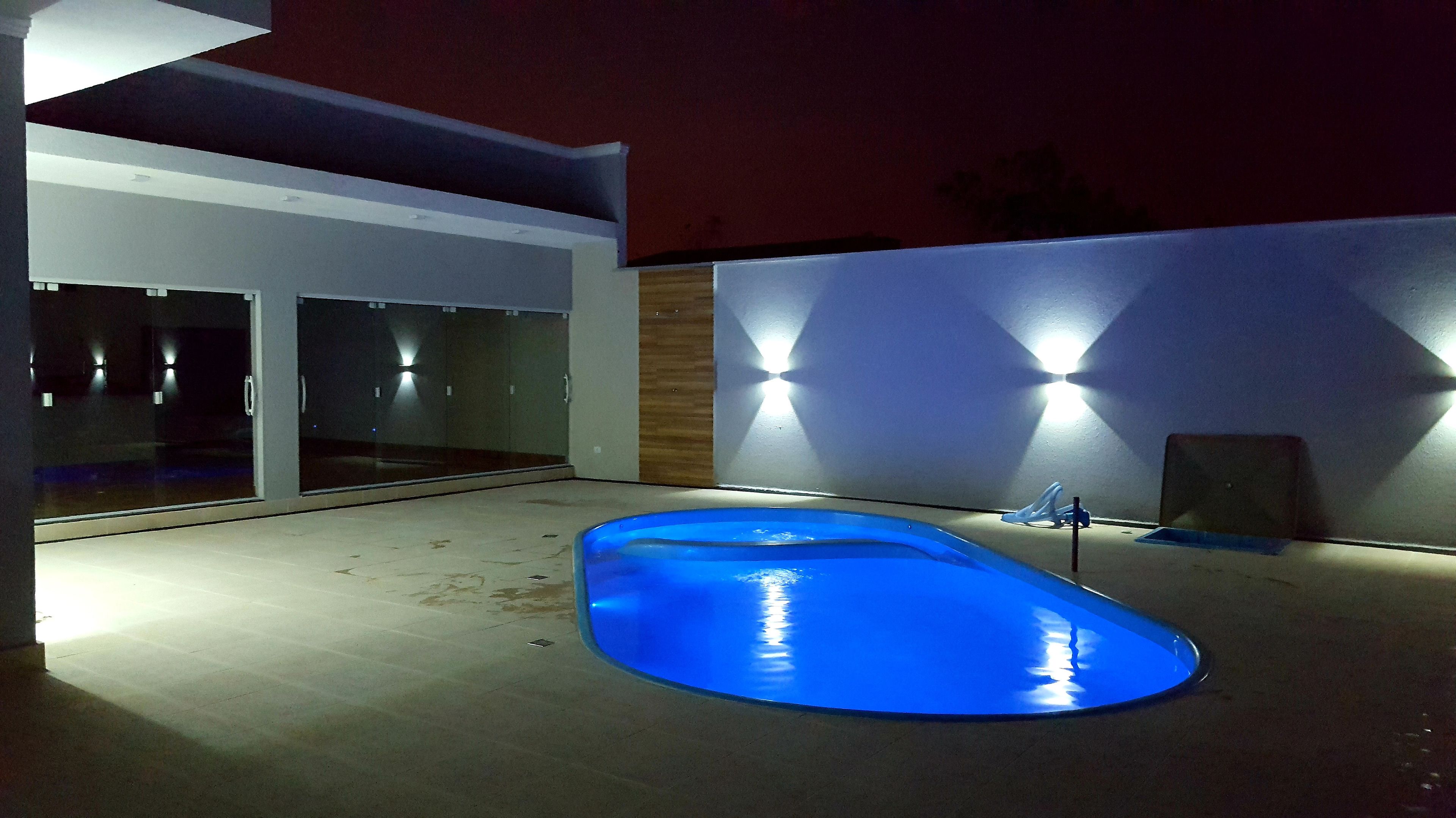 Ein modernes Haus mit Schwimmbad, großen Glasfenstern und Außenbeleuchtung.