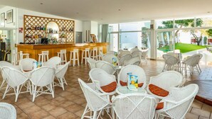 A spacious indoor area with a bar and multiple tables and chairs. - Pateo Village Apartments (Albufeira)