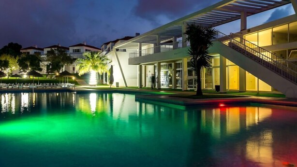 A modern hotel with a swimming pool, outdoor seating, and a staircase leading to the upper floors. - Pateo Village Apartments (Albufeira)