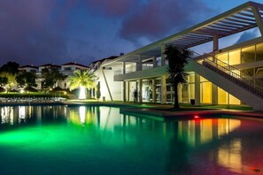A modern hotel with a swimming pool, outdoor seating, and a staircase leading to the upper floors. - Pateo Village Apartments (Albufeira)