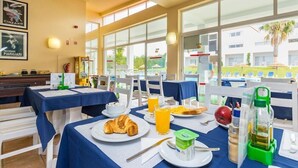 A breakfast setting with tables, breakfast items, and a view of the outside. - Pateo Village Apartments (Albufeira)