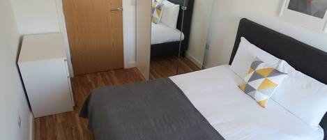 A neatly arranged bedroom with a bed, a wardrobe, and a door.