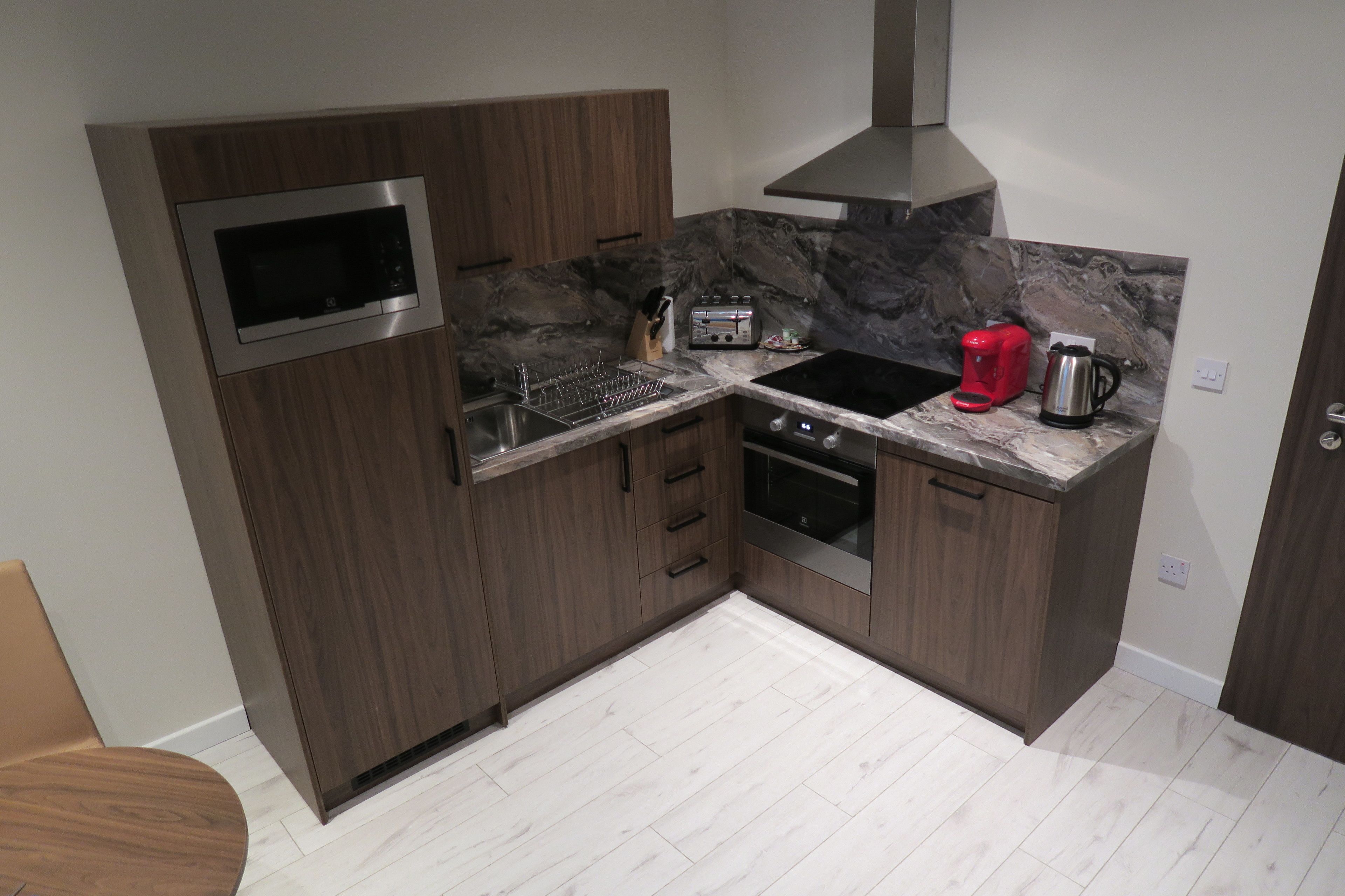 A compact kitchen with a microwave, toaster, coffee maker, and oven.