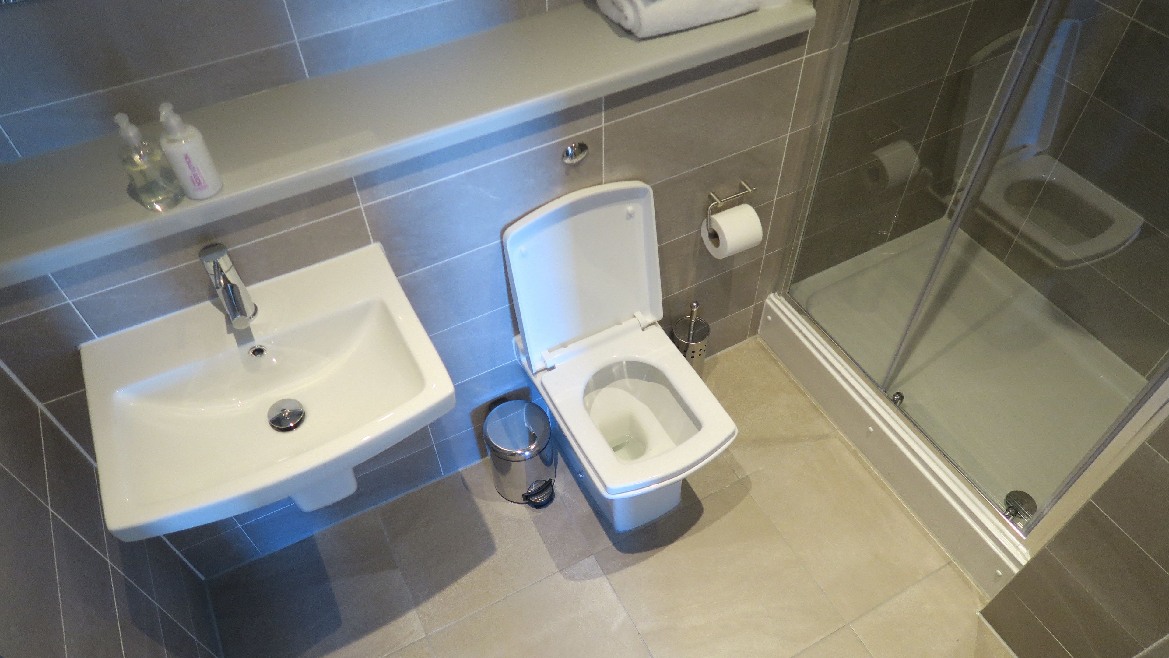 Baño con lavamanos, inodoro y cabina de ducha de vidrio.