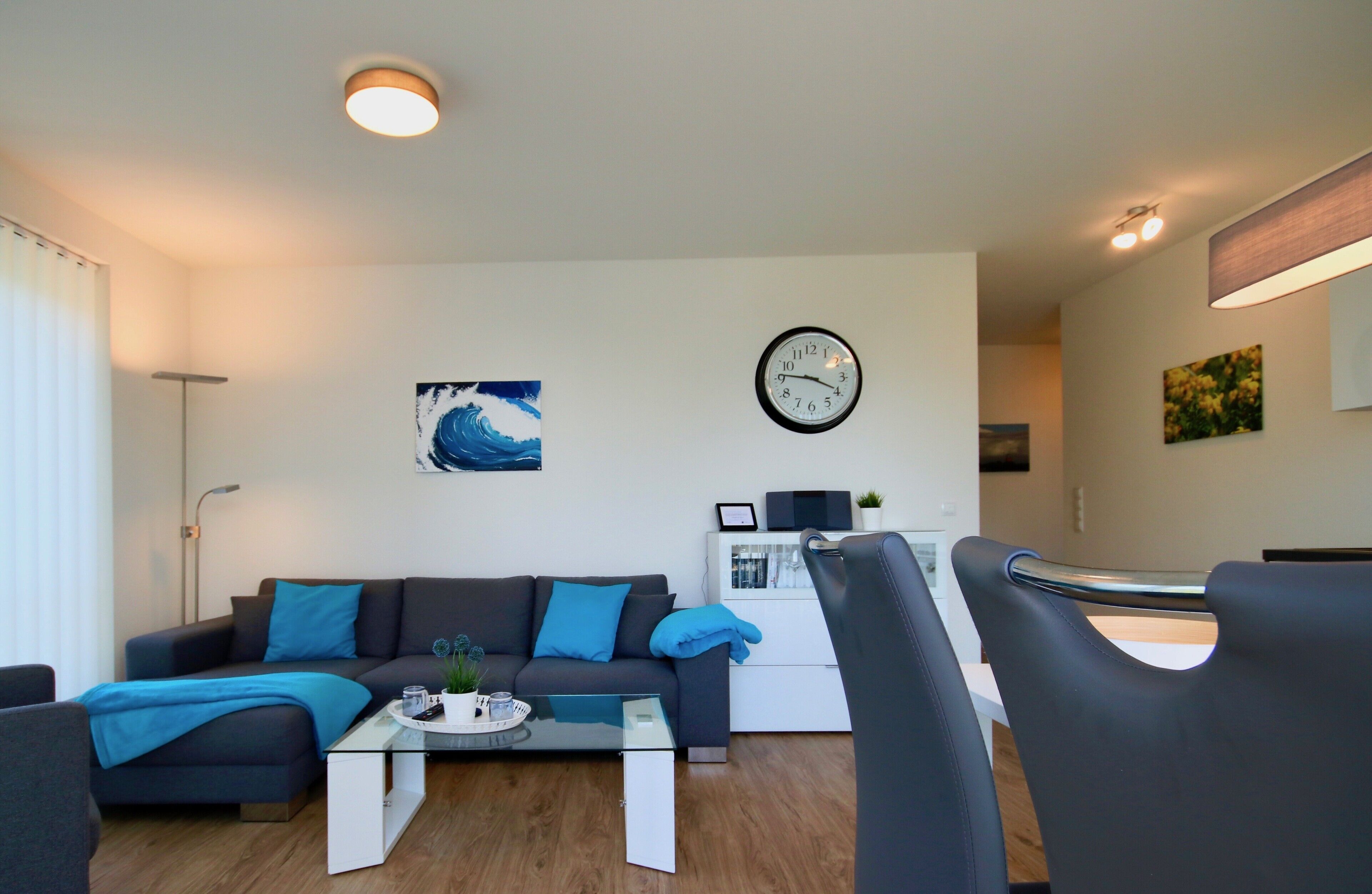 A modern living room with a sofa, coffee table, and a dining area with chairs.