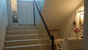 A staircase leading to a reception area with a desk and a vase of flowers. - Villa Karmelia (Darlowo)