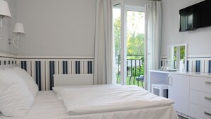 A bedroom with a bed, a bedside table, a dresser, a mirror, and a TV mounted on the wall. - Villa Karmelia (Darlowo)