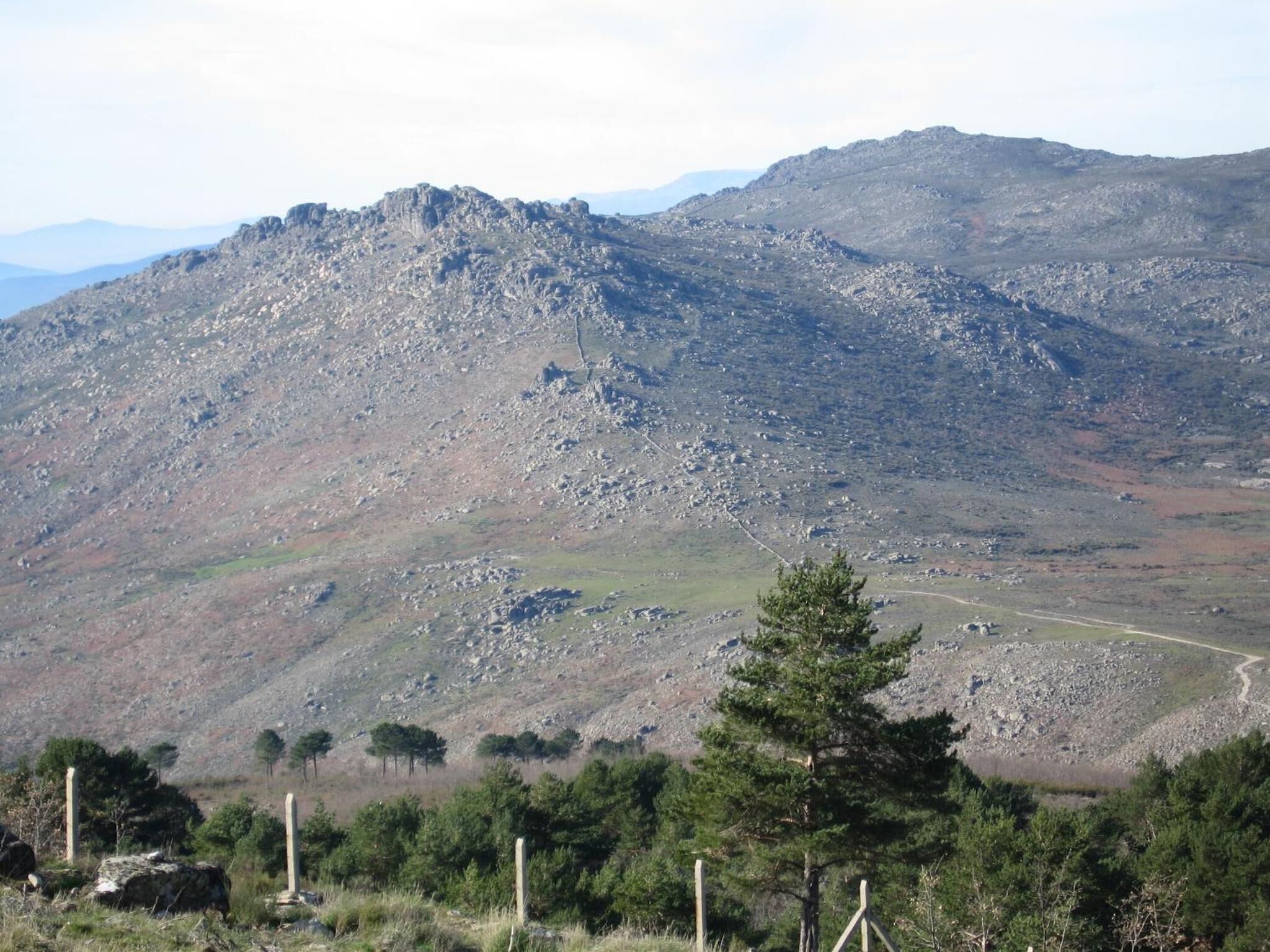 Un paisaje montañoso con terreno rocoso y vegetación escasa.