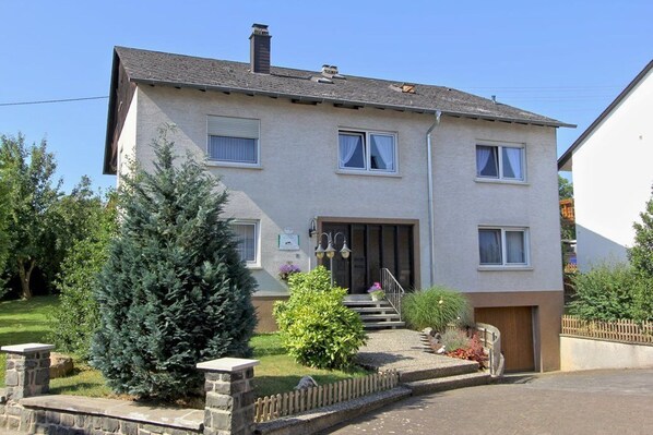 A two-story residential building with a front entrance, a small porch, and a driveway.