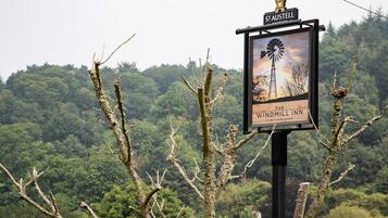 A sign for The Windmill Inn with a windmill illustration, surrounded by trees.