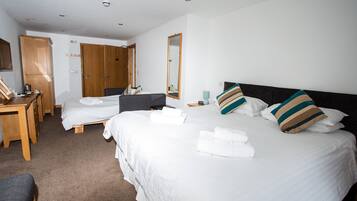 Habitación de hotel con una cama grande, un escritorio, un armario y un espejo.