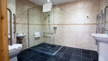 Un baño con ducha de vidrio, lavamanos blanco y un inodoro.