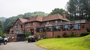 El Windmill Inn, un edificio de ladrillo con un letrero, un aviso de alojamiento cerrado y un coche aparcado.
