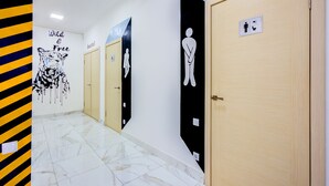 Un pasillo con puertas, un mural en la pared y un letrero que indica un baño.