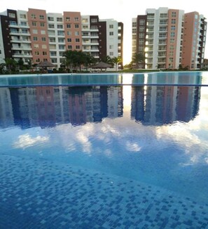 A swimming pool with a clear reflection of surrounding buildings. - Dreams Lagoon Cancun (Cancun)