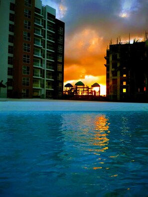A swimming pool with a sunset view, surrounded by high-rise buildings. - Dreams Lagoon Cancun (Cancun)