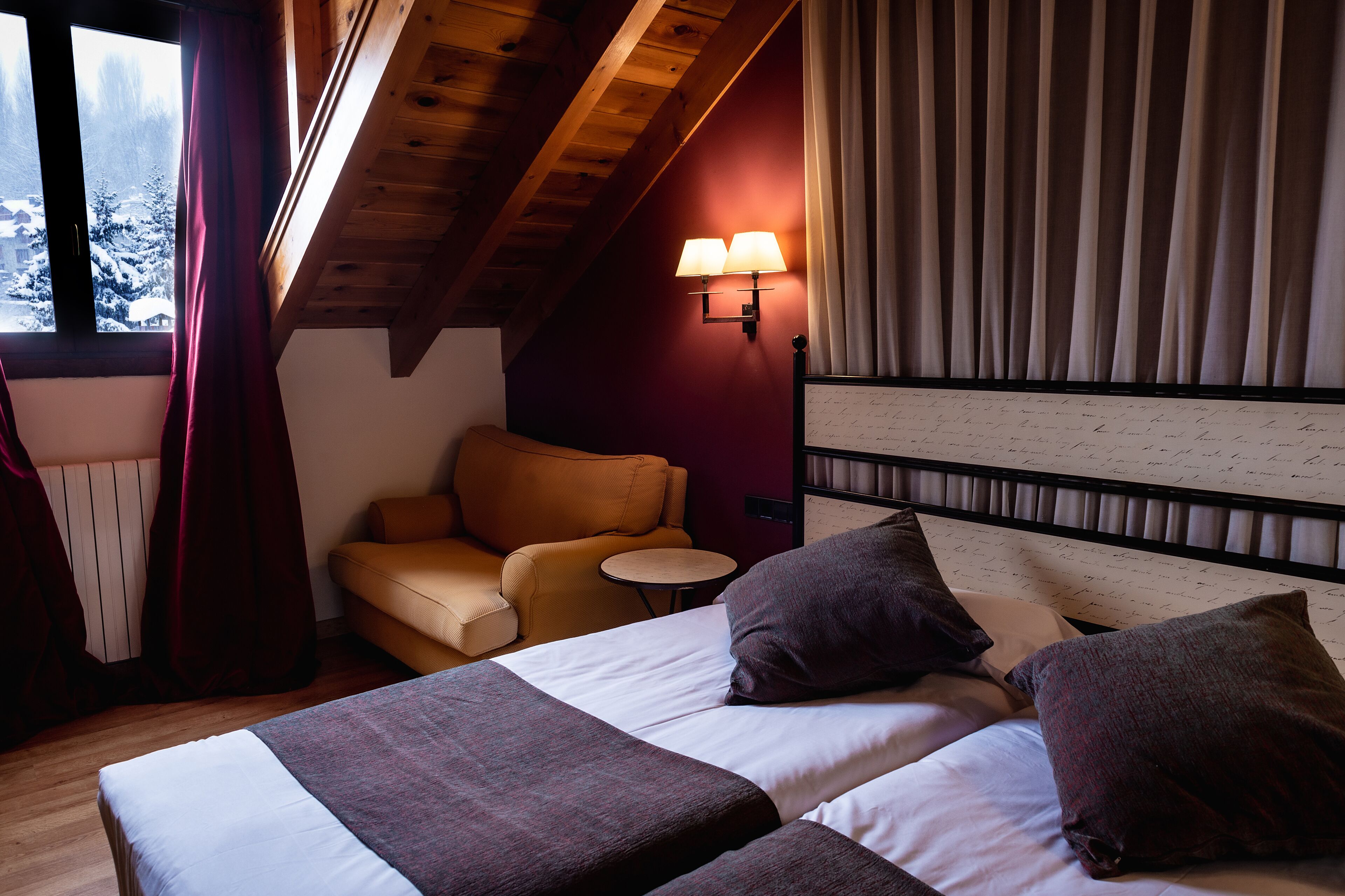 Une pièce confortable avec un lit, une chaise, une petite table et une lampe.