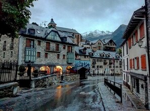 A historic town square with stone buildings, a fountain, and a mountain backdrop. - Hotel Valle De Izas (Sallent de Gallego)