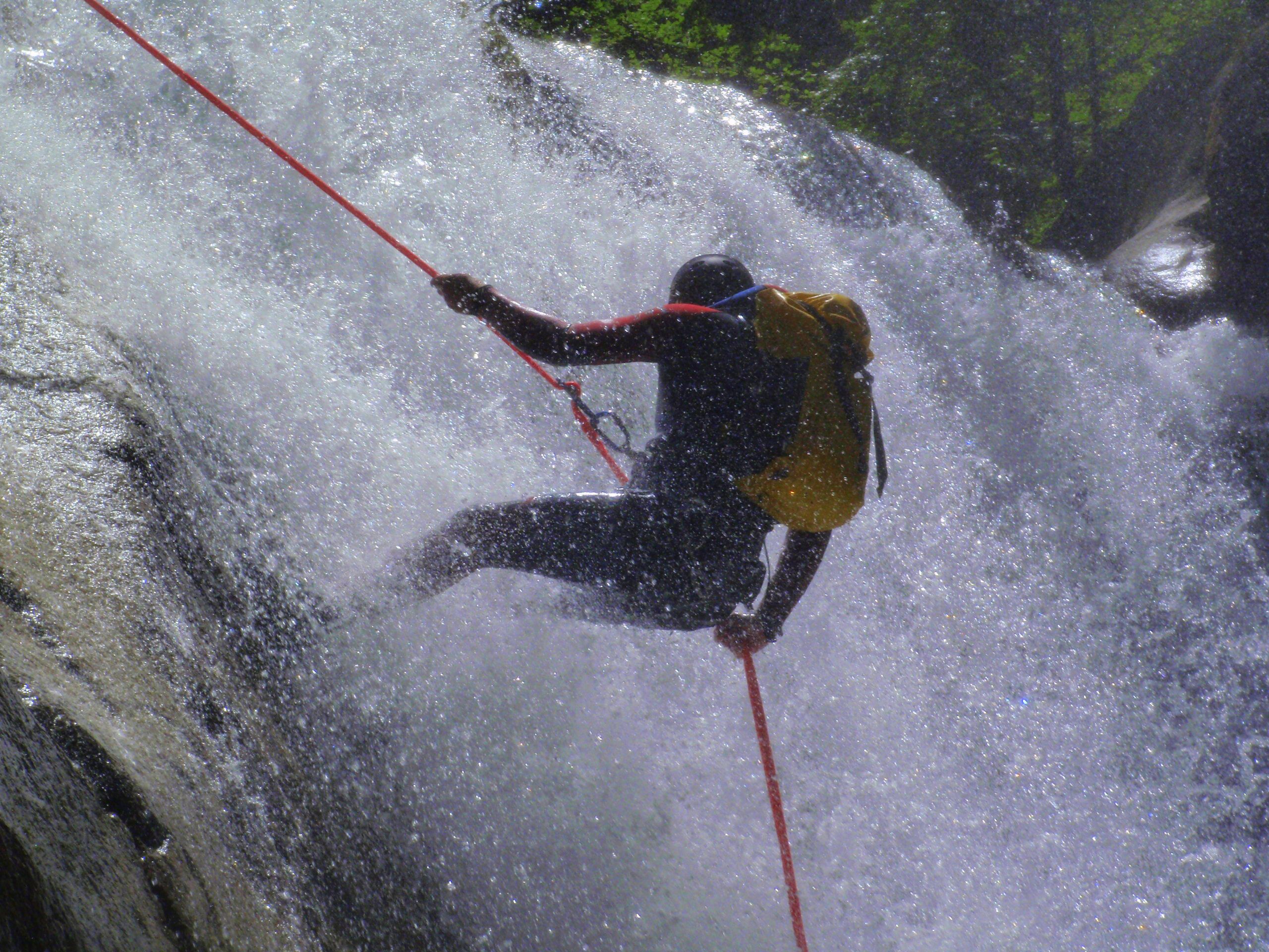 Una persona descendiendo en rappel por una cascada.
