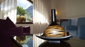 A modern living room with a large window, a sofa, a chair, and a decorative vase on a glass table. - Hotel Valle De Izas (Sallent de Gallego)
