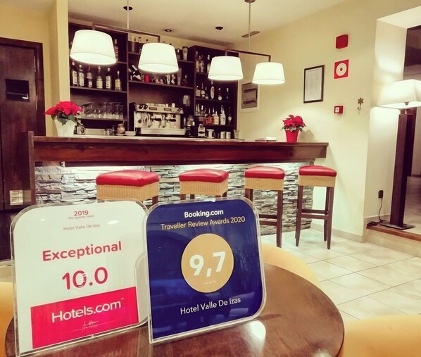 Hotellin vastaanottotila, jossa on bari, punaisilla pehmusteilla varustetut jakkarat ja kyltti, jossa kerrotaan, että hotelli on saanut Booking.com-sivustolta arvosanan 9,7 vuoden 2020 Traveller Review Awards -palkintojen perusteella.