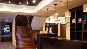 A hotel reception area with a wooden staircase, a reception desk, and a sign indicating a restaurant. - Hotel Valle De Izas (Sallent de Gallego)