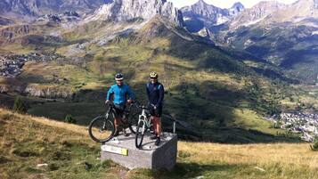 Due ciclisti in piedi su un monumento in pietra con un paesaggio montuoso sullo sfondo.