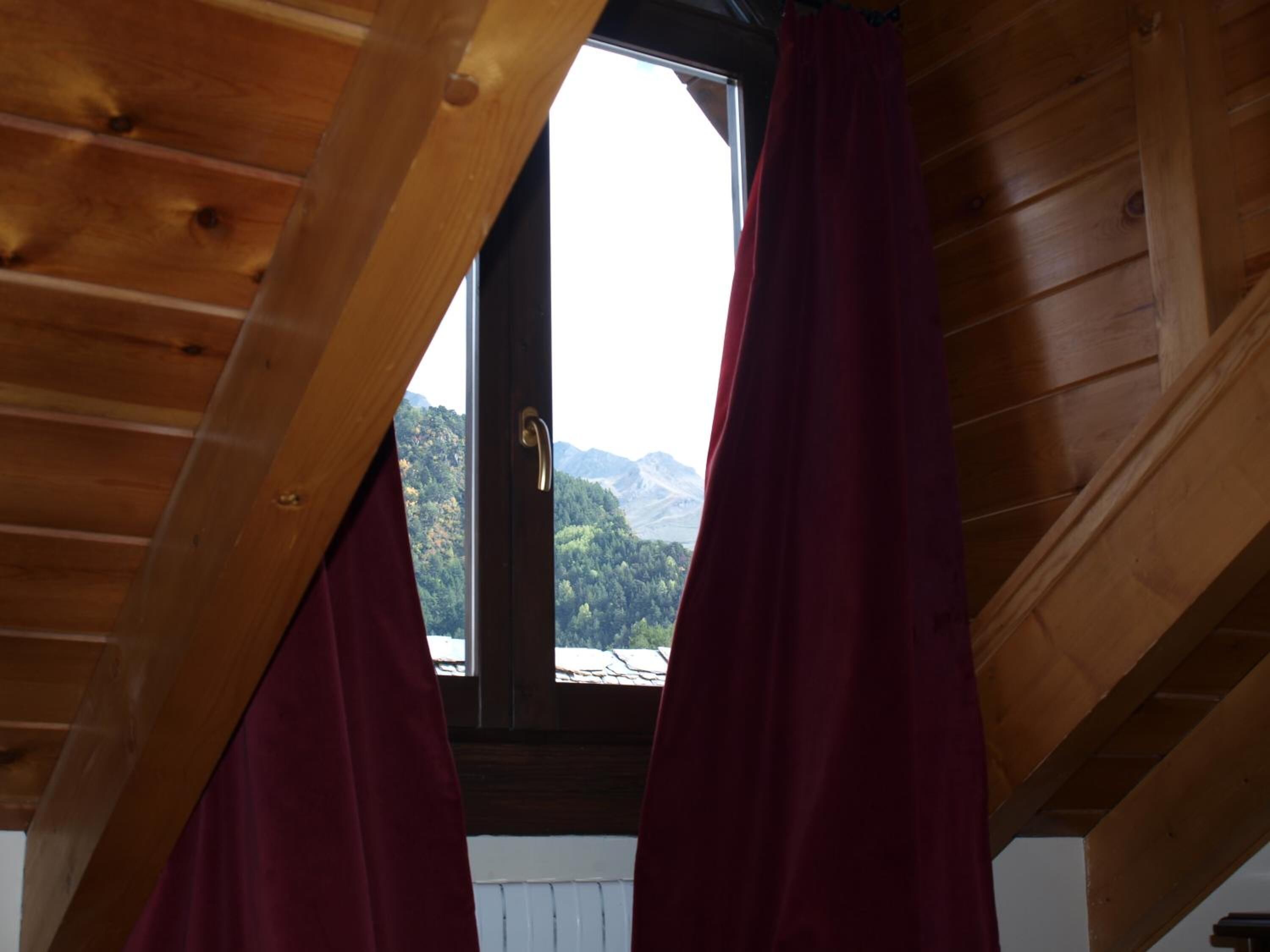 A wooden ceiling with a window and curtains.