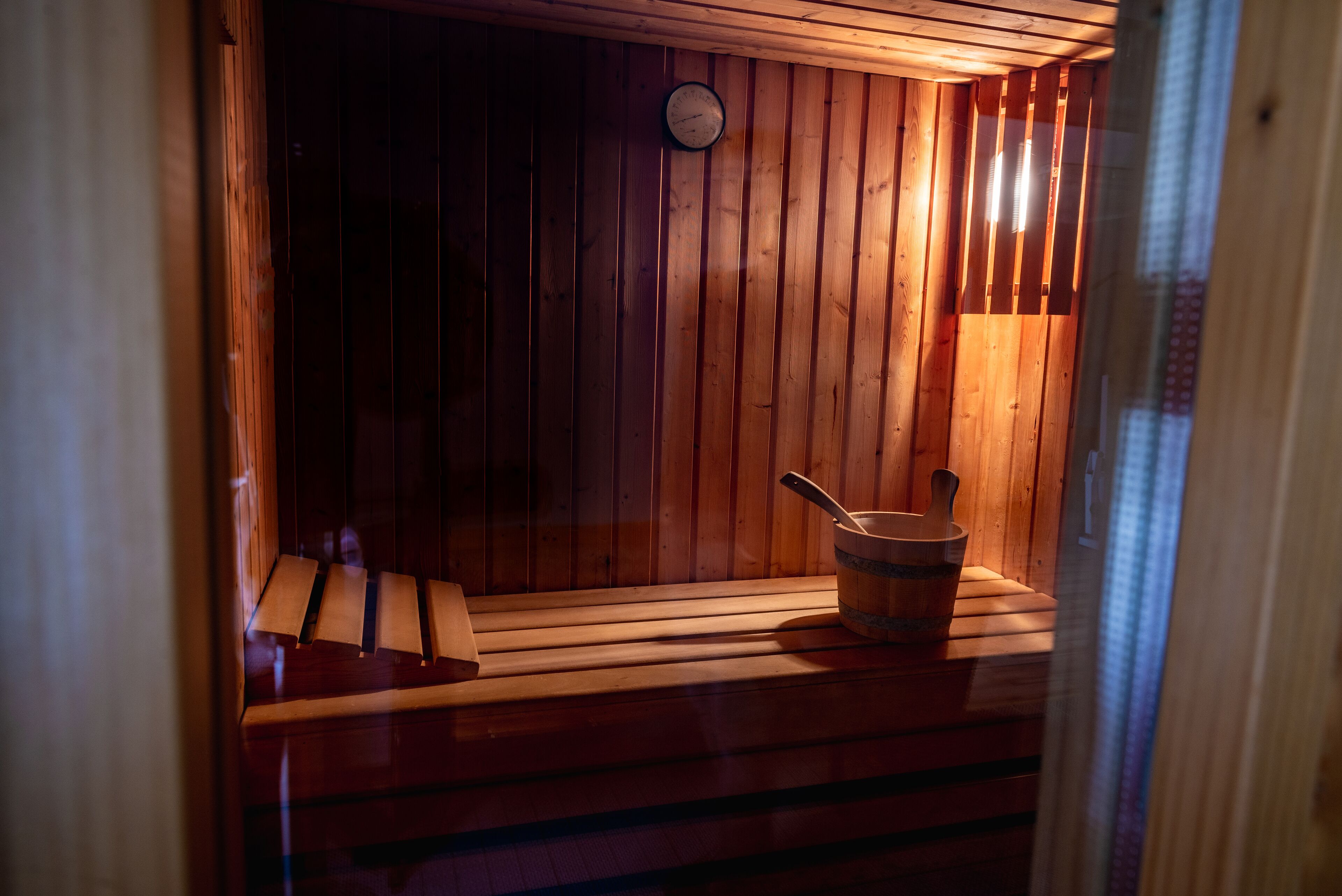 Een sauna met houten banken en een houten emmer.