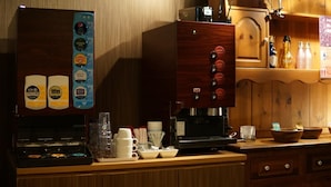 Una estación de café con una máquina de café, tazas y una variedad de bebidas.