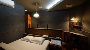 Una habitación de hotel con cama, mesita de noche, escritorio y espejo.