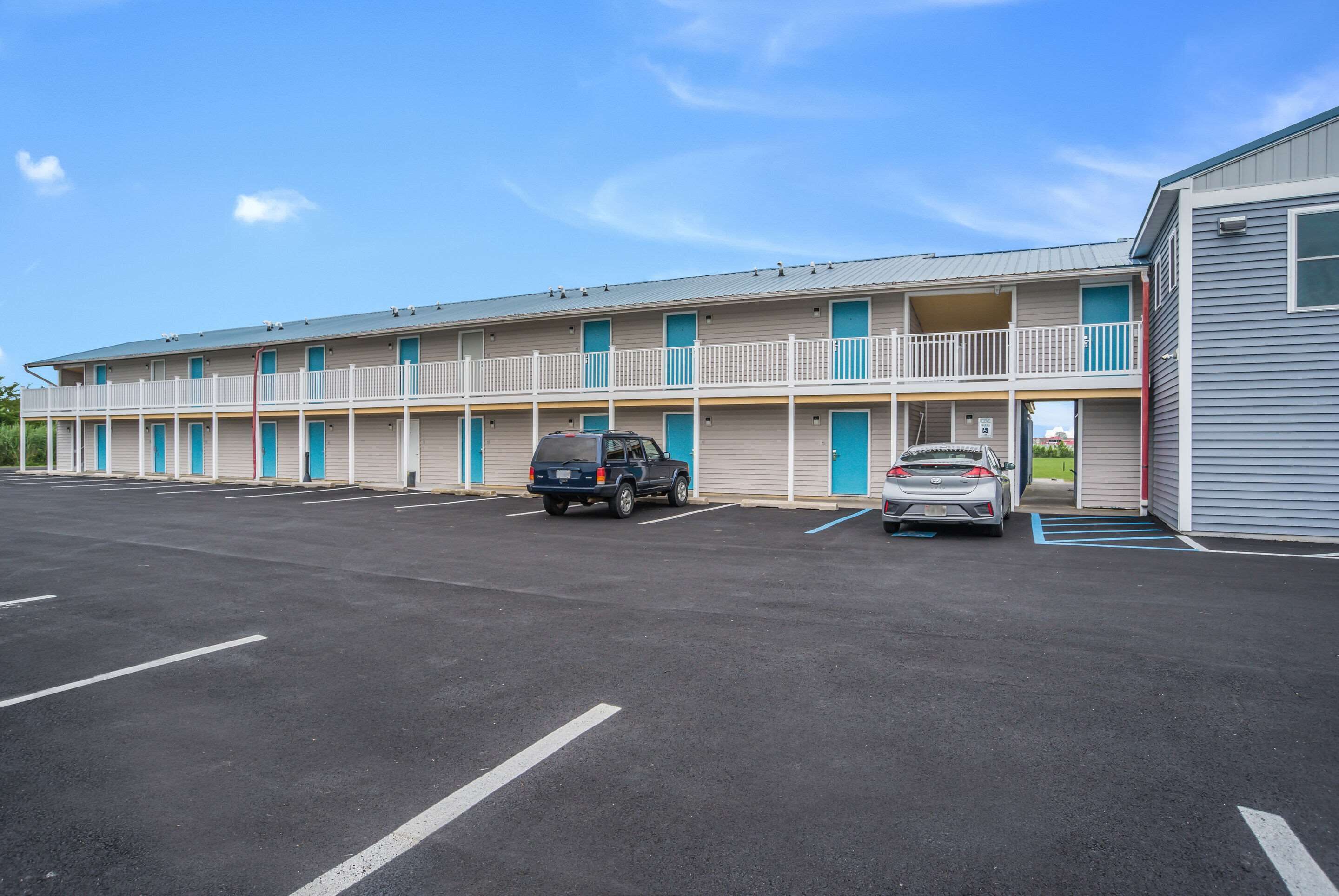 A motel with multiple rooms, a parking lot, and a small building adjacent to the main structure.