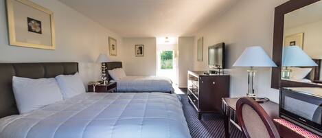 A hotel room with two beds, a desk with a chair, a television, and a dresser.