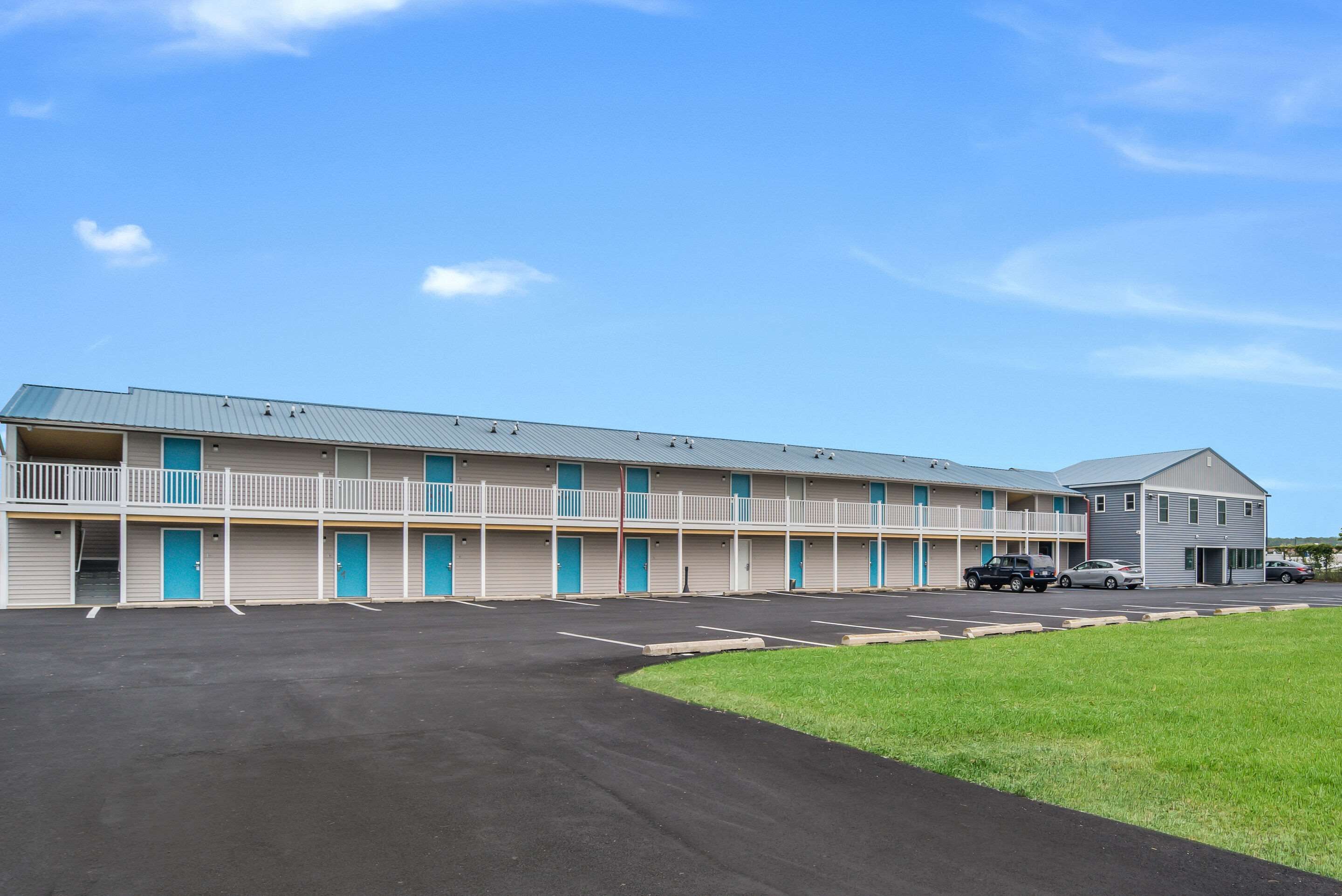 A motel with a two-story structure, multiple rooms, and a parking lot.