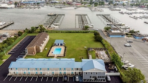 A marina with boats docked, a swimming pool, and a building with a parking lot. - Rodeway Inn at Somers Cove Marina (Crisfield)