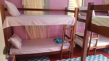 Dormitorio con literas, piso a cuadros, ventana con cortinas y escalera de madera.