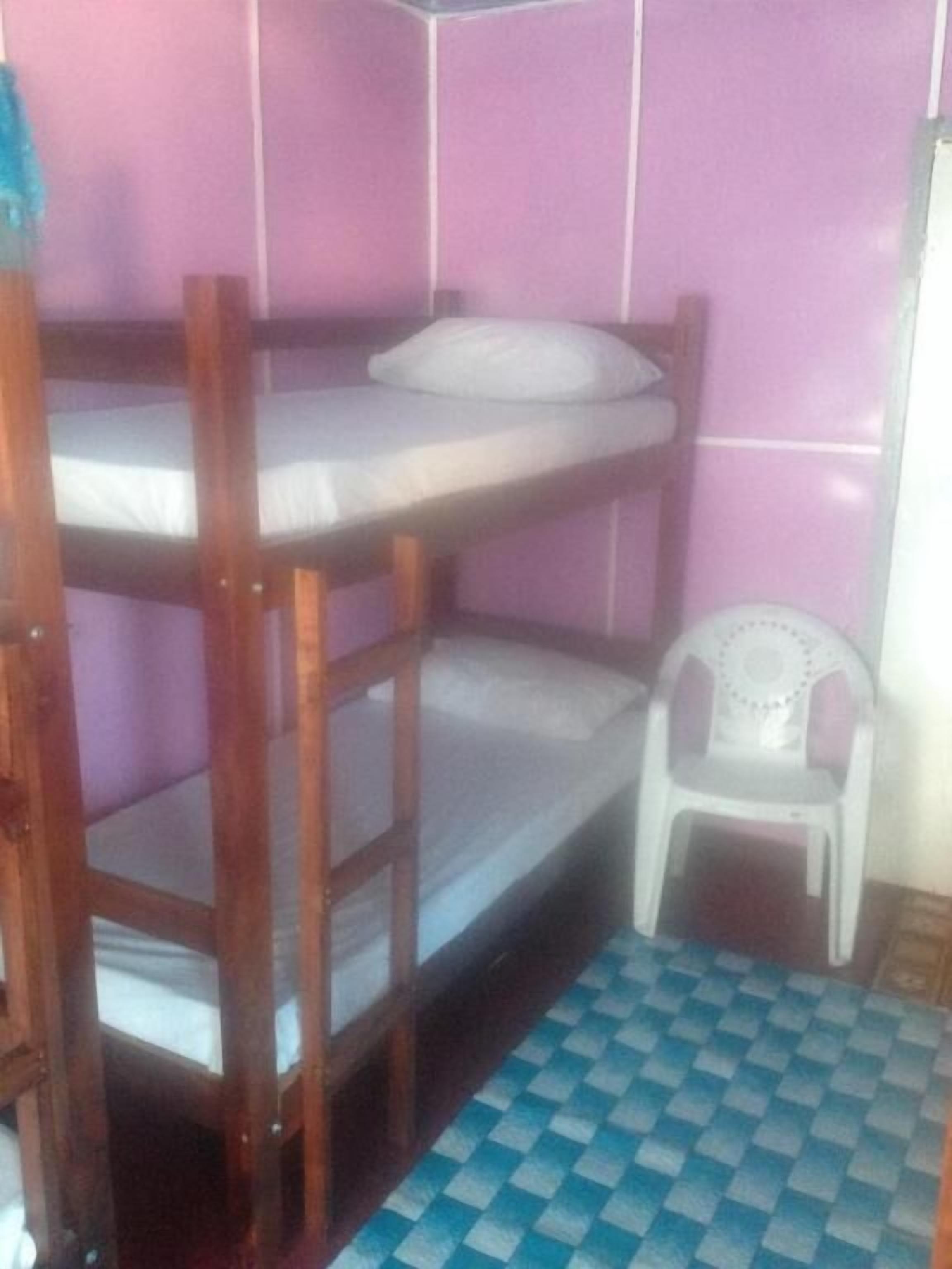 A bunk bed room with a checkered floor, a small white chair, and pink walls.