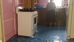 Una cocina compacta con estufa a gas, horno blanco y pileta.