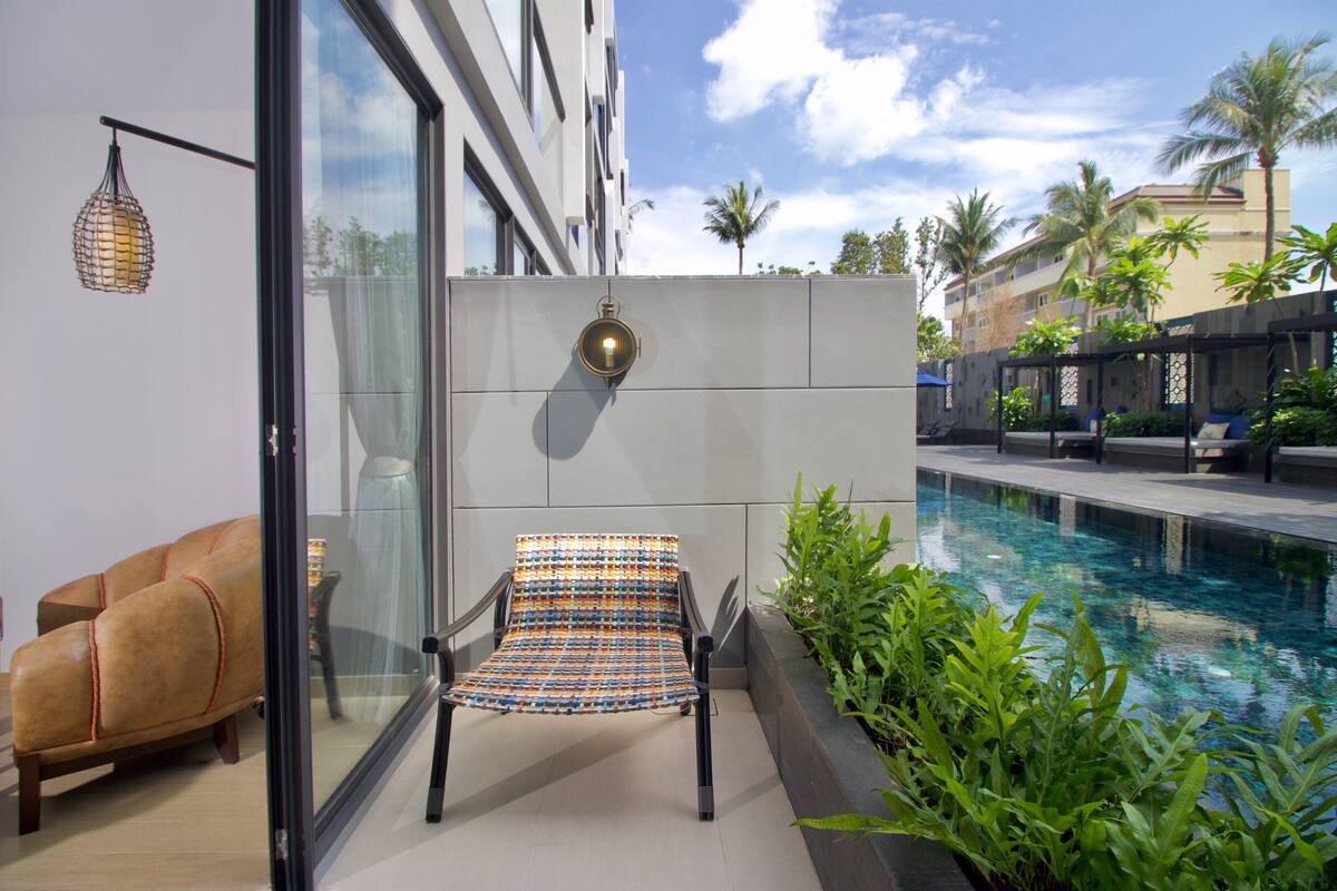 A modern outdoor seating area with a pool, a lounge chair, and a wall-mounted light fixture.