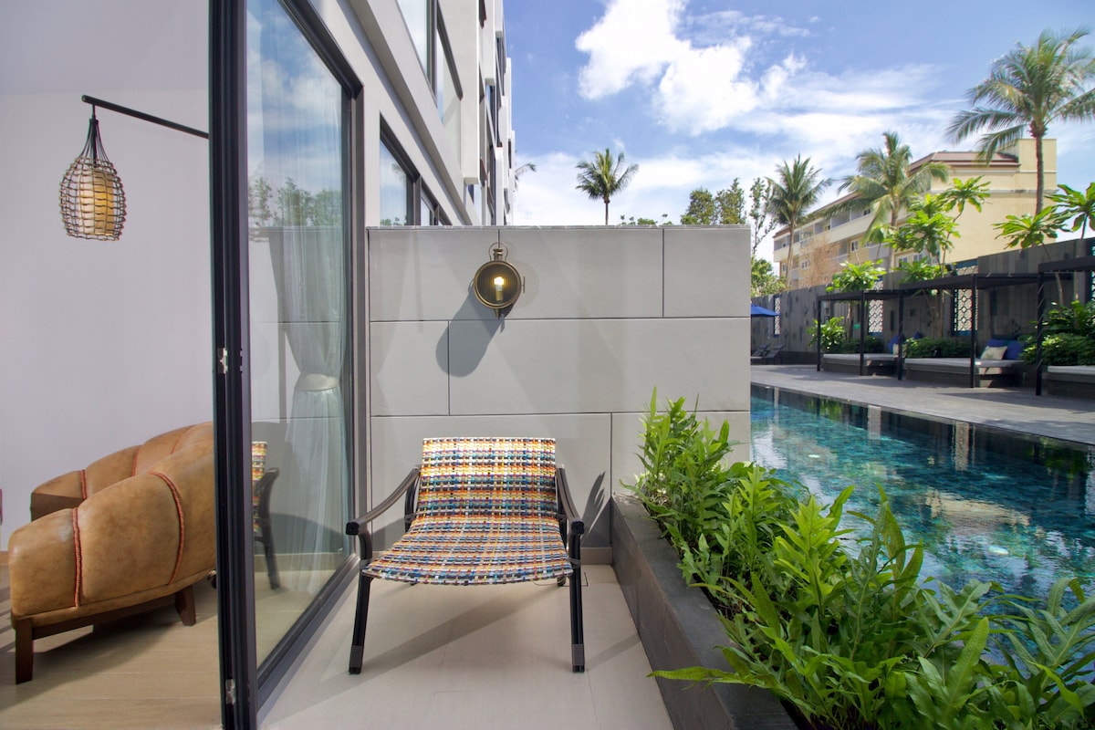 A modern outdoor seating area with a pool, a lounge chair, and a wall-mounted light fixture.