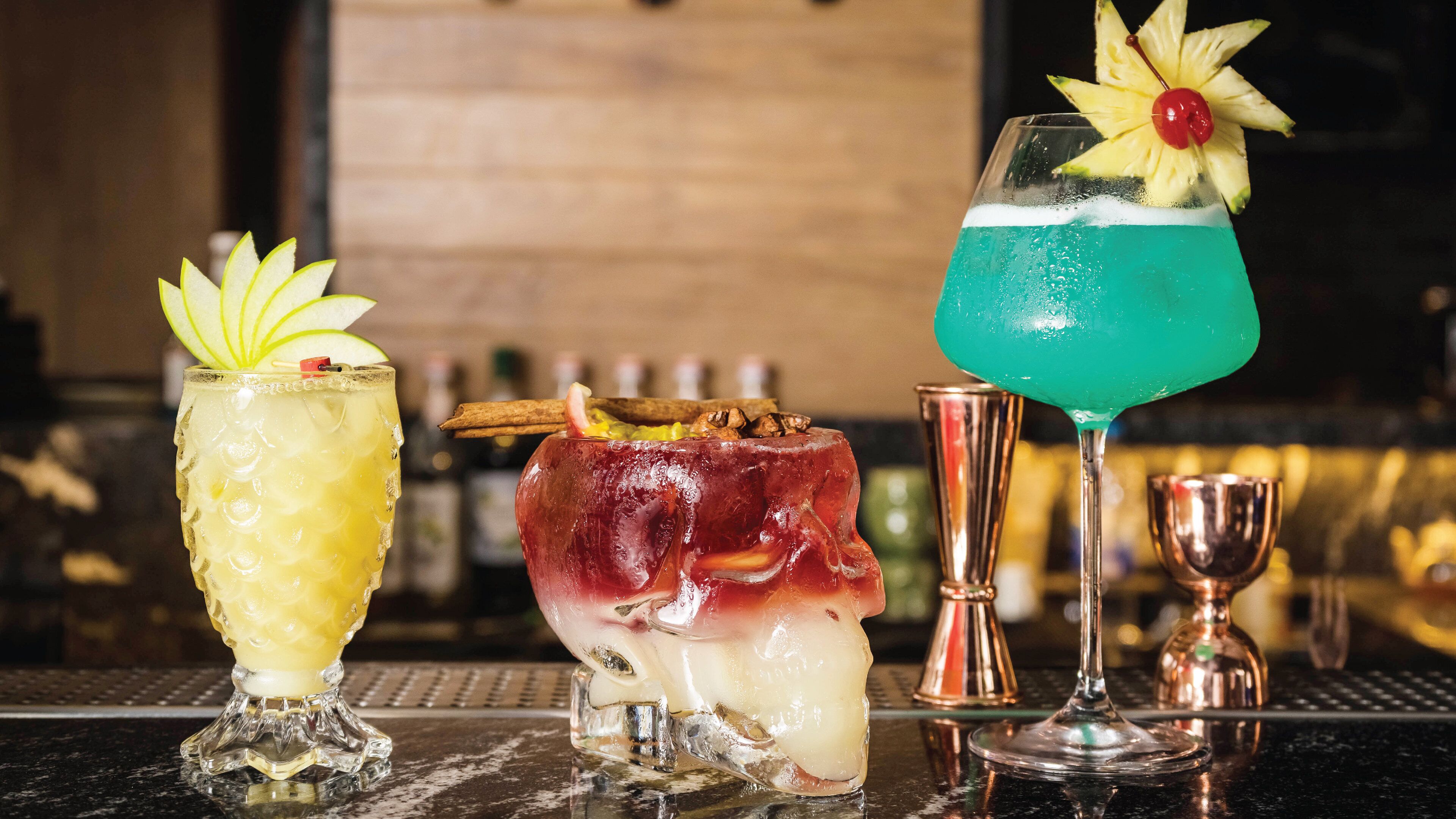 Drie cocktails op een barkruk met een onscherpe achtergrond.