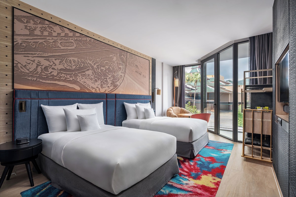 Una habitación de hotel moderna con dos camas, un ventanal grande y vistas al exterior.