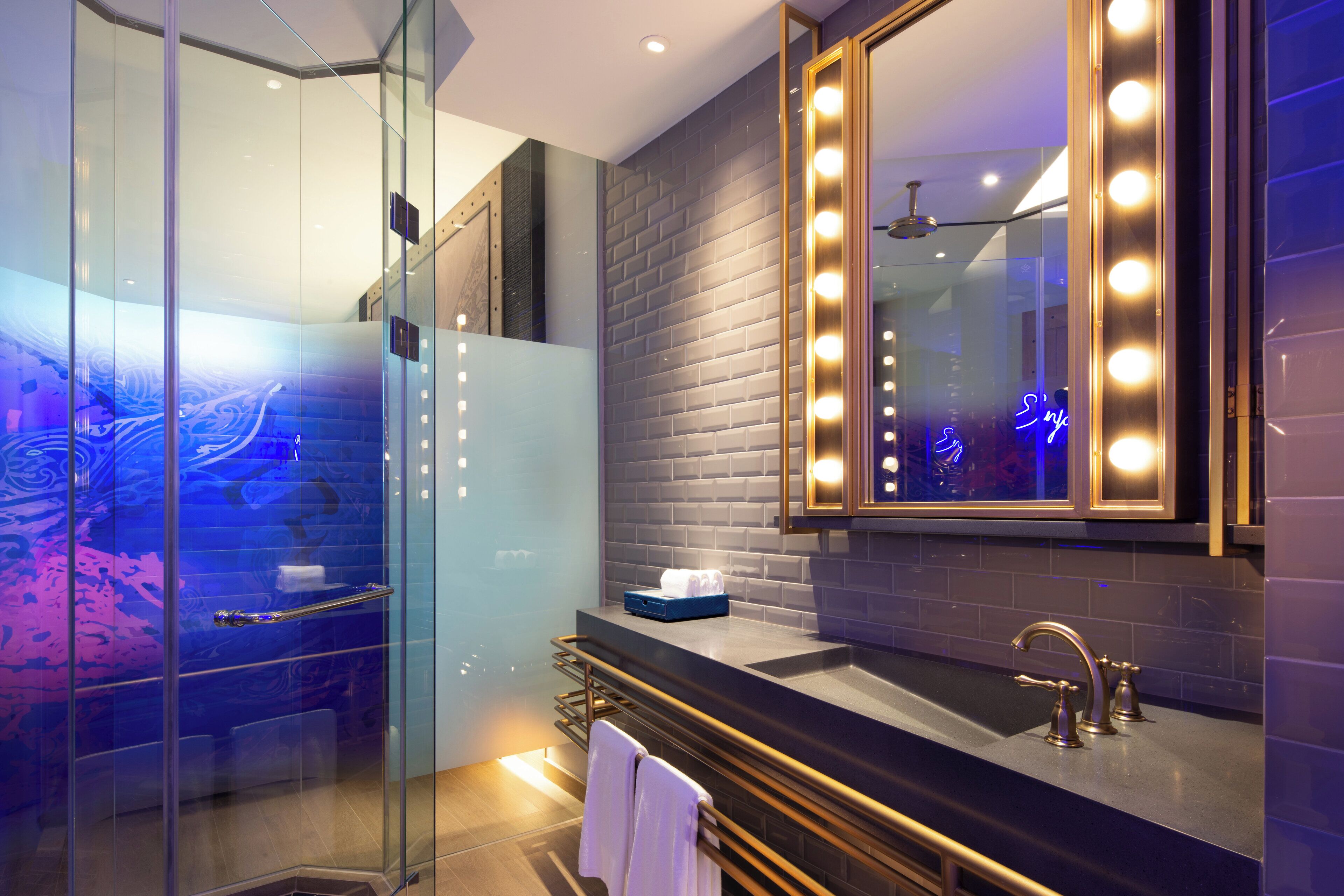 A modern bathroom with a glass shower enclosure, a vanity with a mirror, and a sink with a faucet.