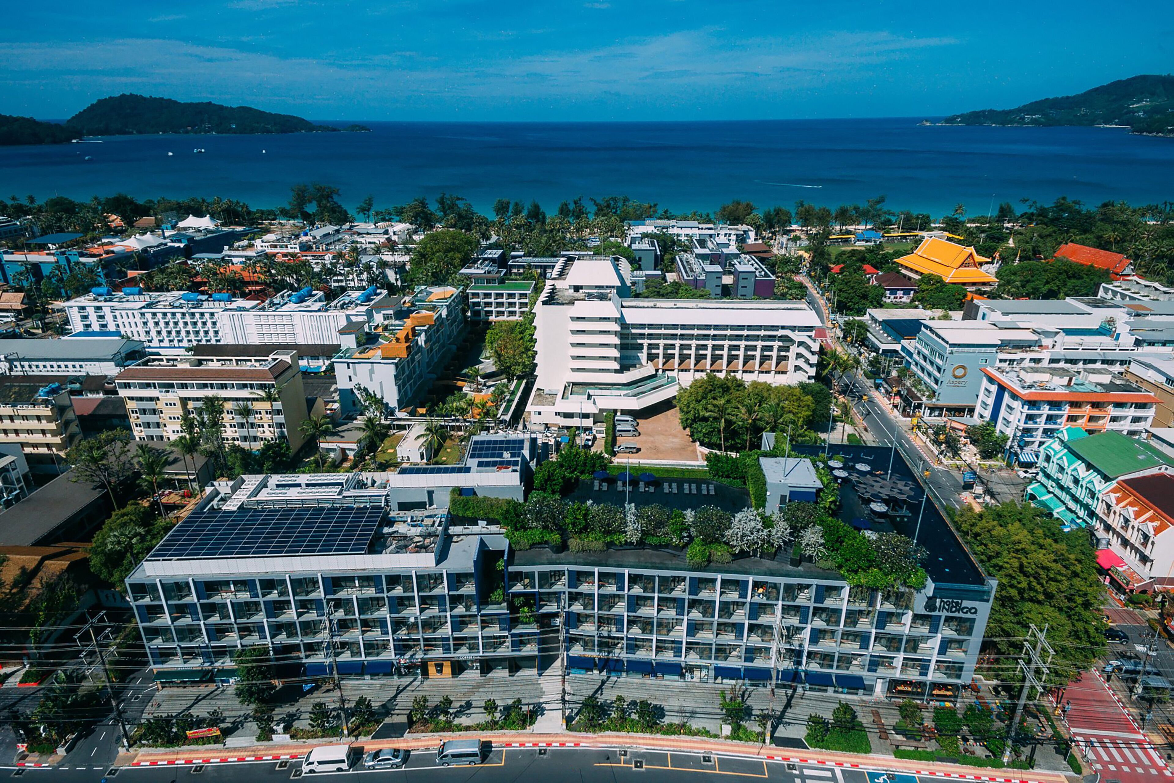 Un paisaje urbano costero con un hotel destacado de diseño moderno, rodeado de una densa construcción y vista al mar.