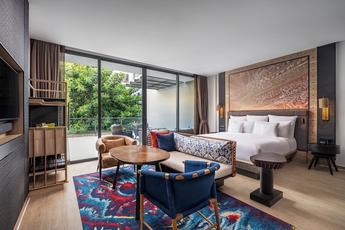 Una habitación de hotel moderna con una cama grande, un sofá, una mesa de comedor y un televisor.