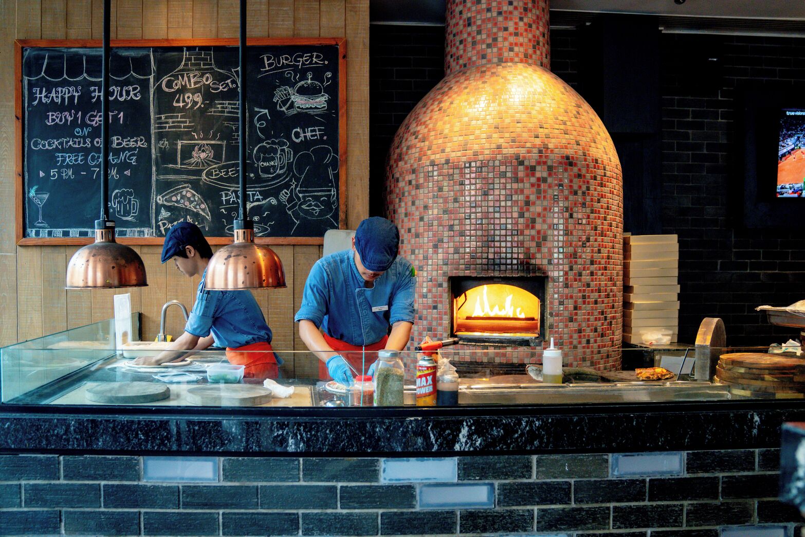 A brick oven pizza restaurant with two chefs preparing food.